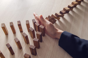 Businesswoman hand stopping the domino wooden effect concept for business